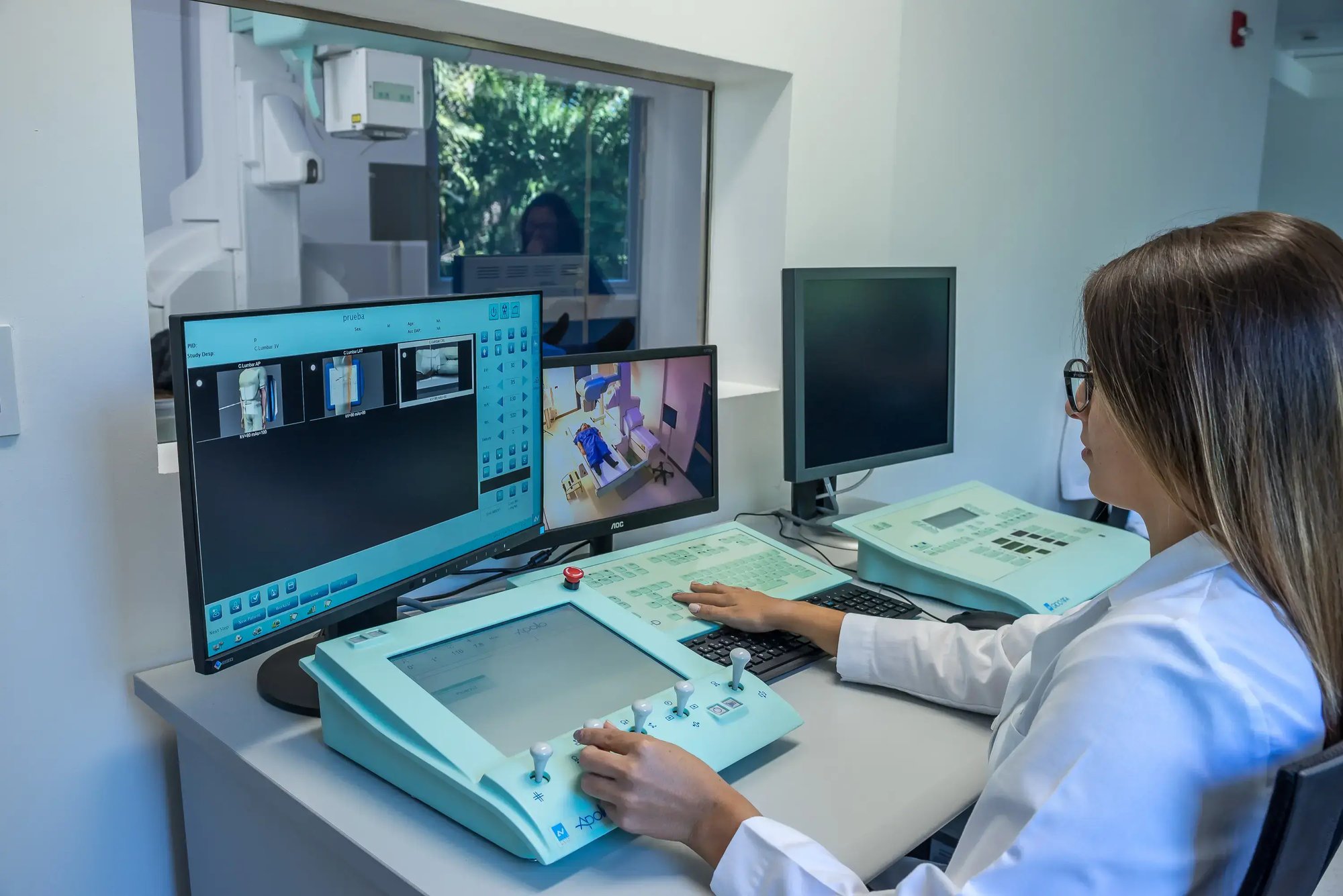 Técnica médica controlando equipo de imagenología desde una sala de monitoreo Técnica médica controlando equipo de imagenología desde una sala de monitoreo
