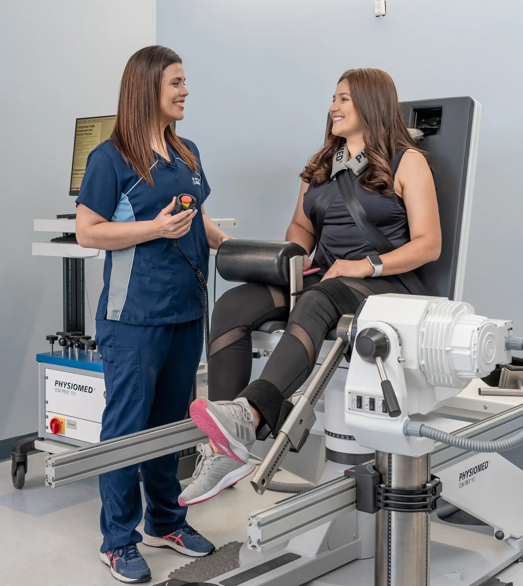 Paciente en máquina de fisioterapia de fuerza supervisada por especialista.