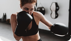 Mujer entrenando boxeo con guantes negros en gimnasio