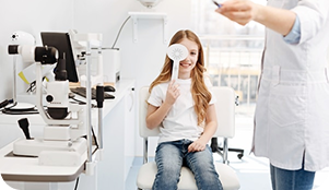 Niña en examen oftalmológico cubriéndose un ojo en consultorio de optometría