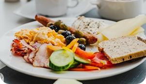 Plato de desayuno saludable con huevos, vegetales, pan y embutidos