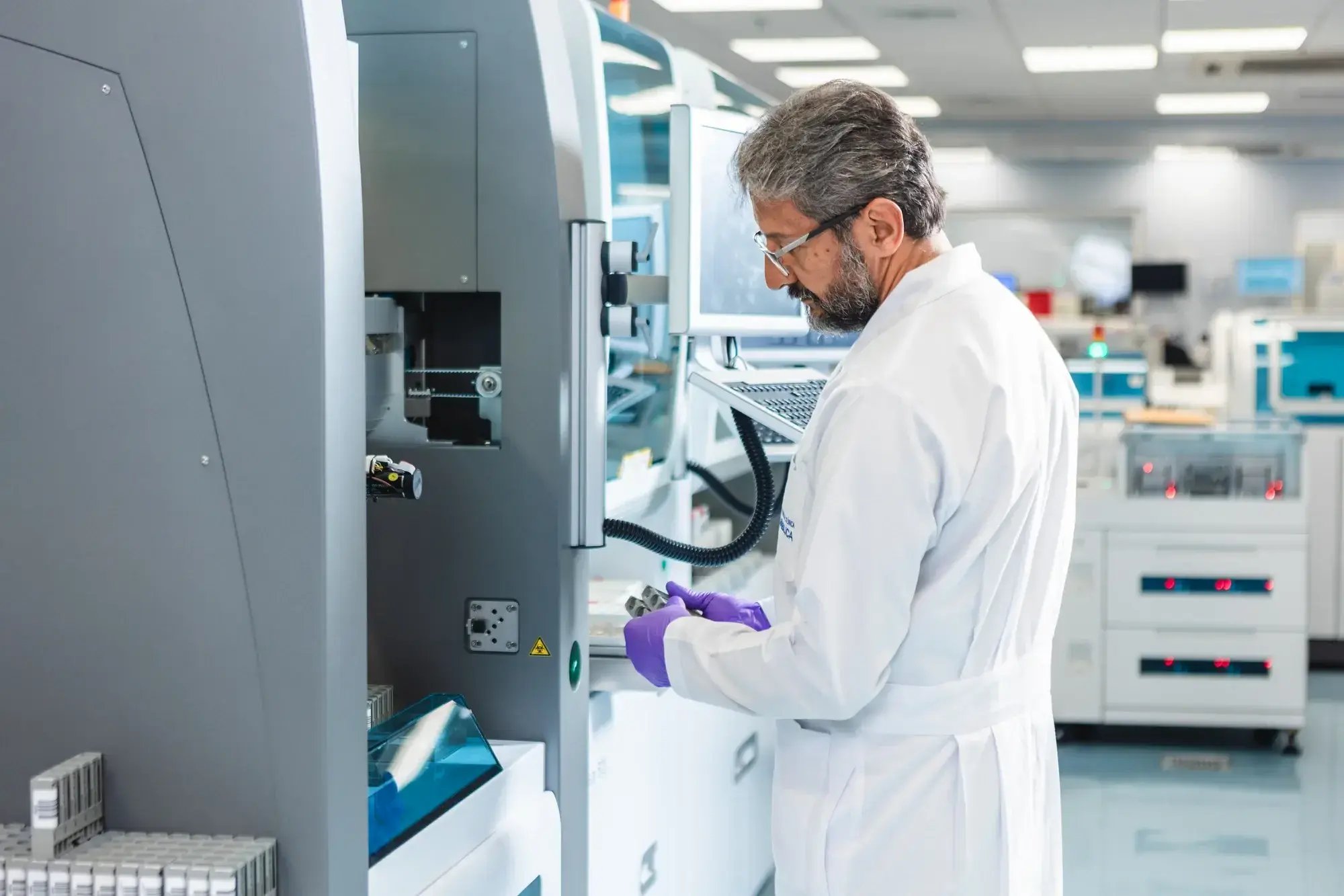 Médico con bata blanca trabajando en máquina de laboratorio clínico