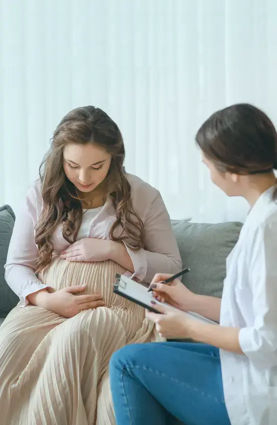 Consulta médica prenatal con mujer embarazada y profesional de salud tomando notas