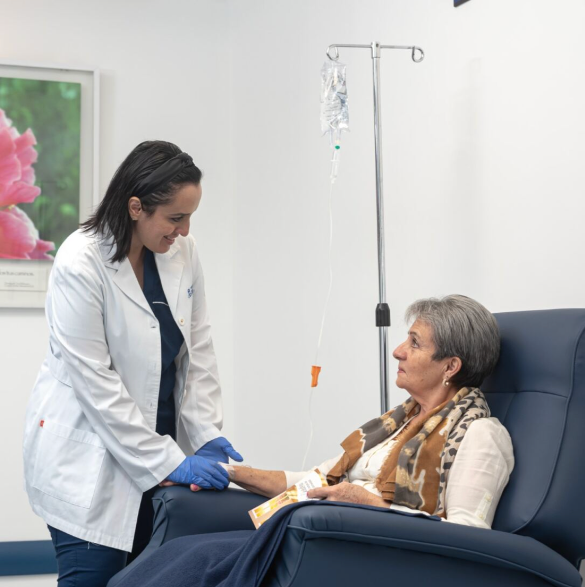 Doctora atendiendo a paciente adulta mayor durante tratamiento intravenoso en clínica