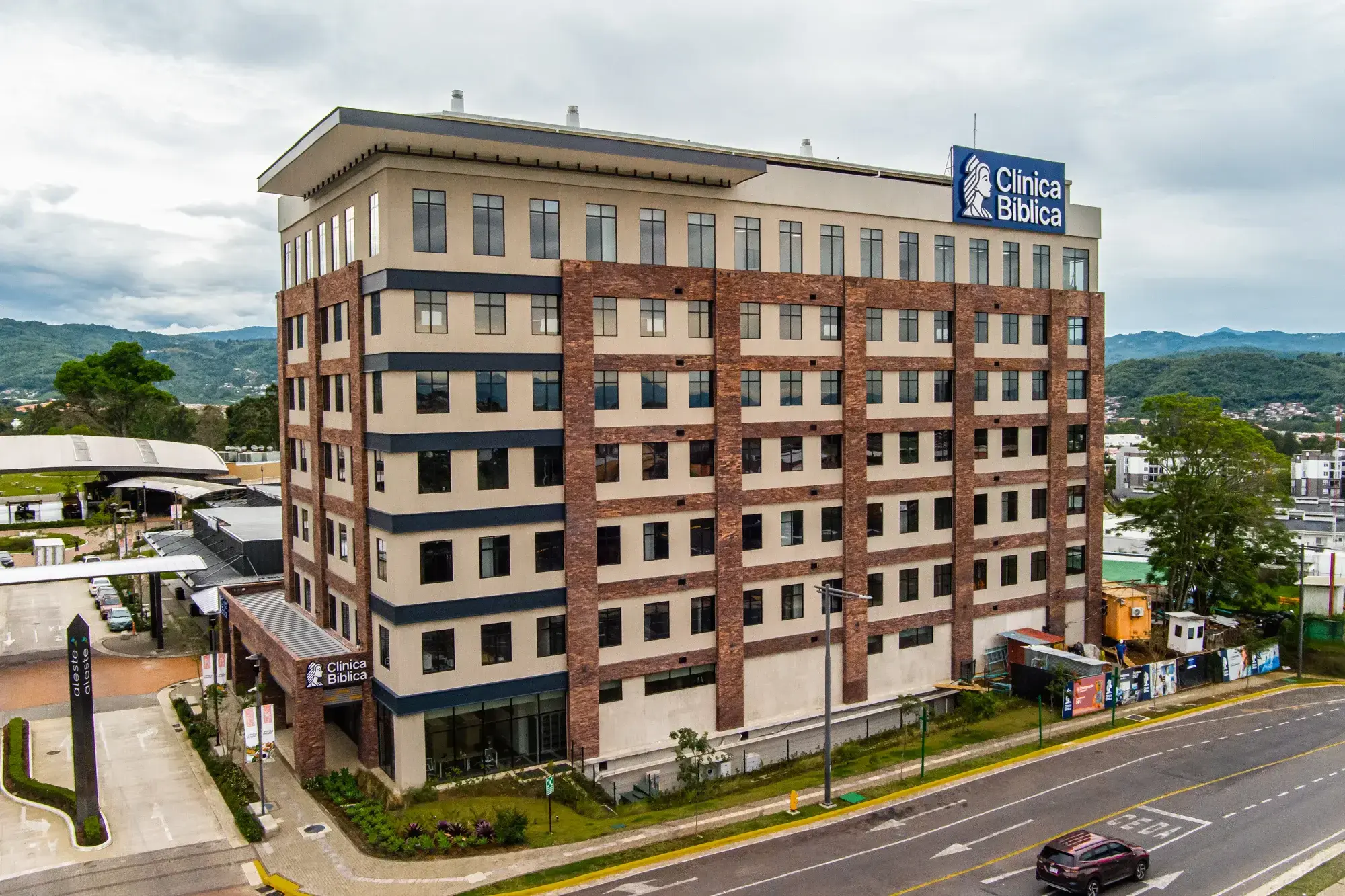 Fachada del edificio de la sede Aleste de la Clínica Bíblica en Curridabat bajo cielo nublado.